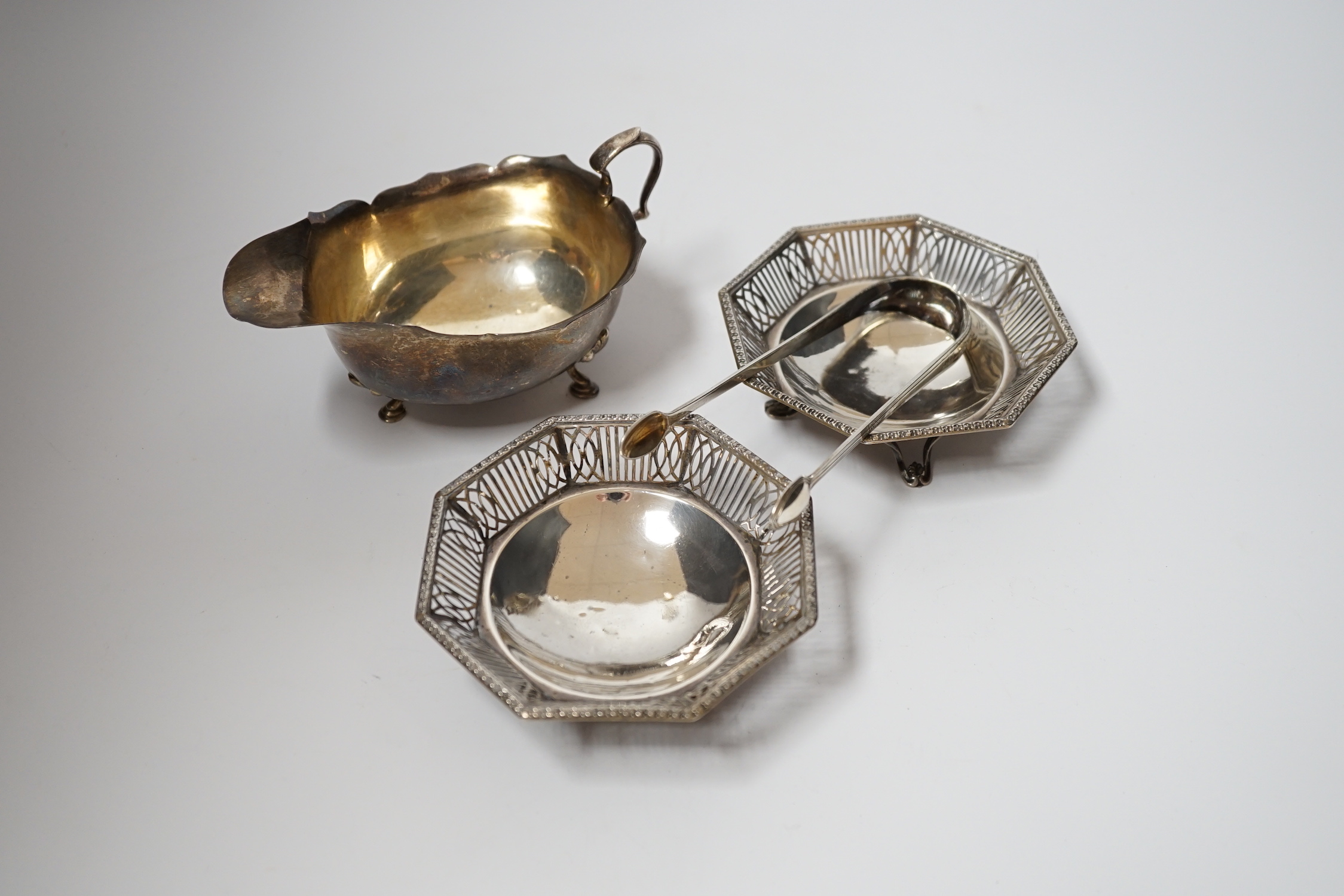 A George V silver sauce boat, Adie Bros. Birmingham, 1925, a pair of George V pierced silver bonbon dishes, Mappin & Webb, Birmingham 1930, 10.2cm and a pair of Georgian silver sugar tongs.